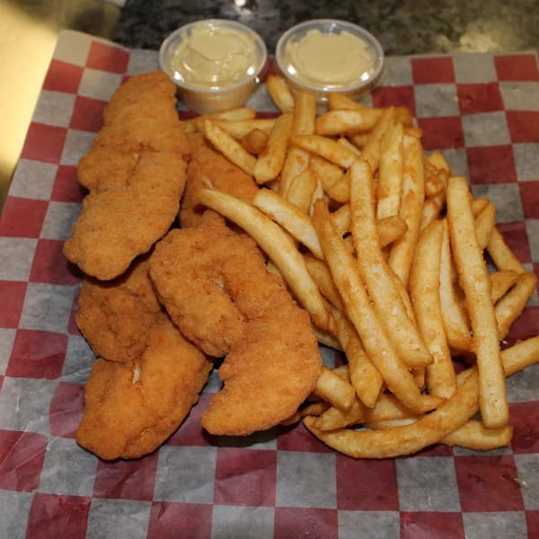 Golden-brown fried chicken tenders and french fries served with two dipping sauces on checkered paper.